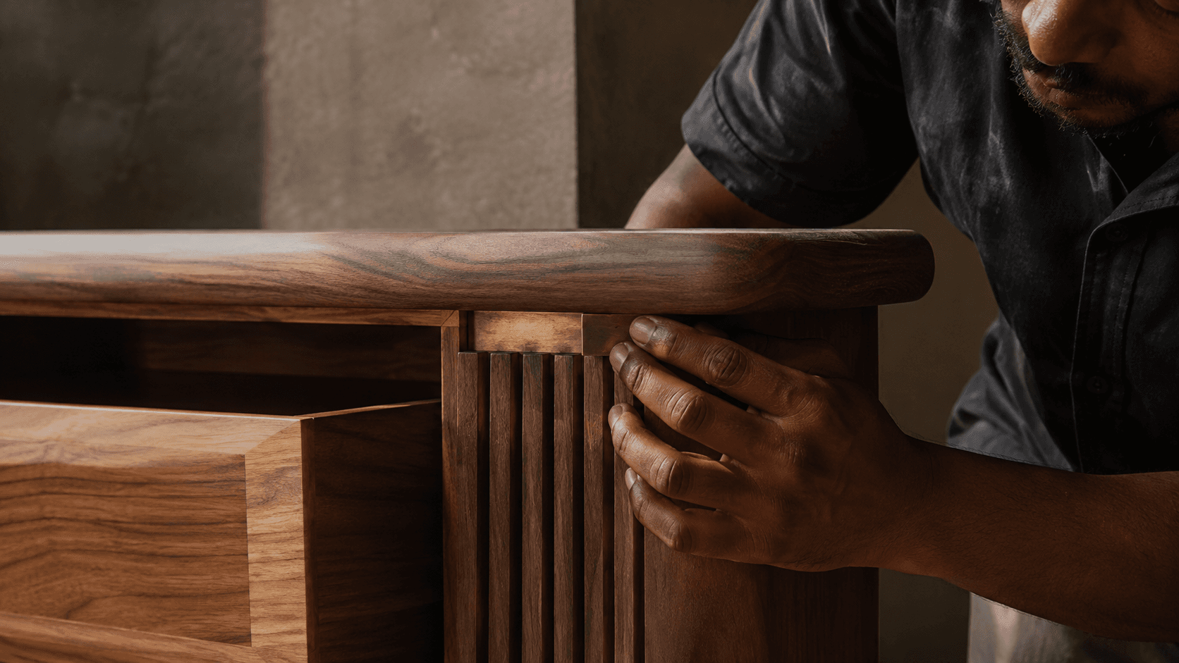 A craftsperson refining the timber and brass detail of a cabinet